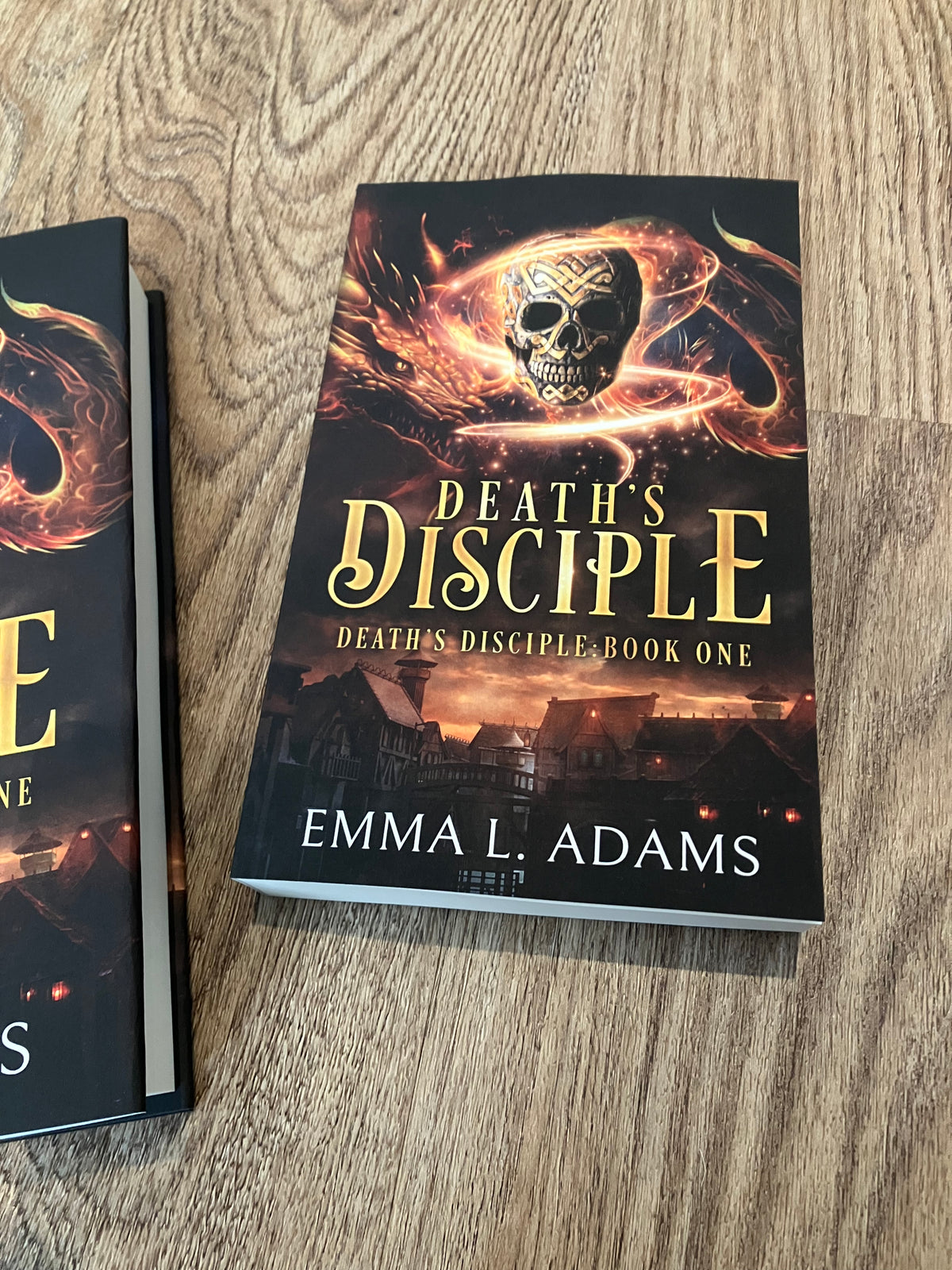 A paperback of Death's Disciple lying on a wood grain floor